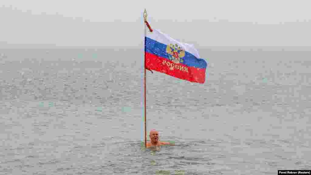 Один із учасників запливу увійшов у воду з прапором Росії