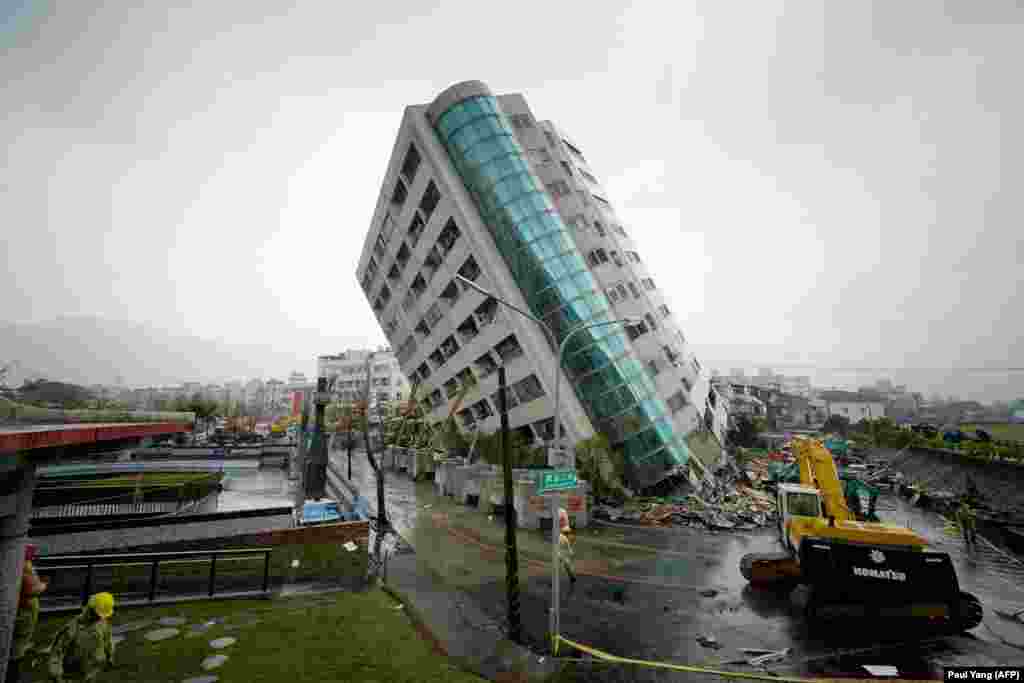 Rescue workers block off the area outside a building which tilted to one side after its foundation collapsed during a strong earthquake in the Taiwanese city of Hualien. (AFP/Paul Yang)