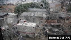 Afghan security security officers are seen through the shattered window of a maternity hospital after gunmen attacked in Kabul on May 12. 