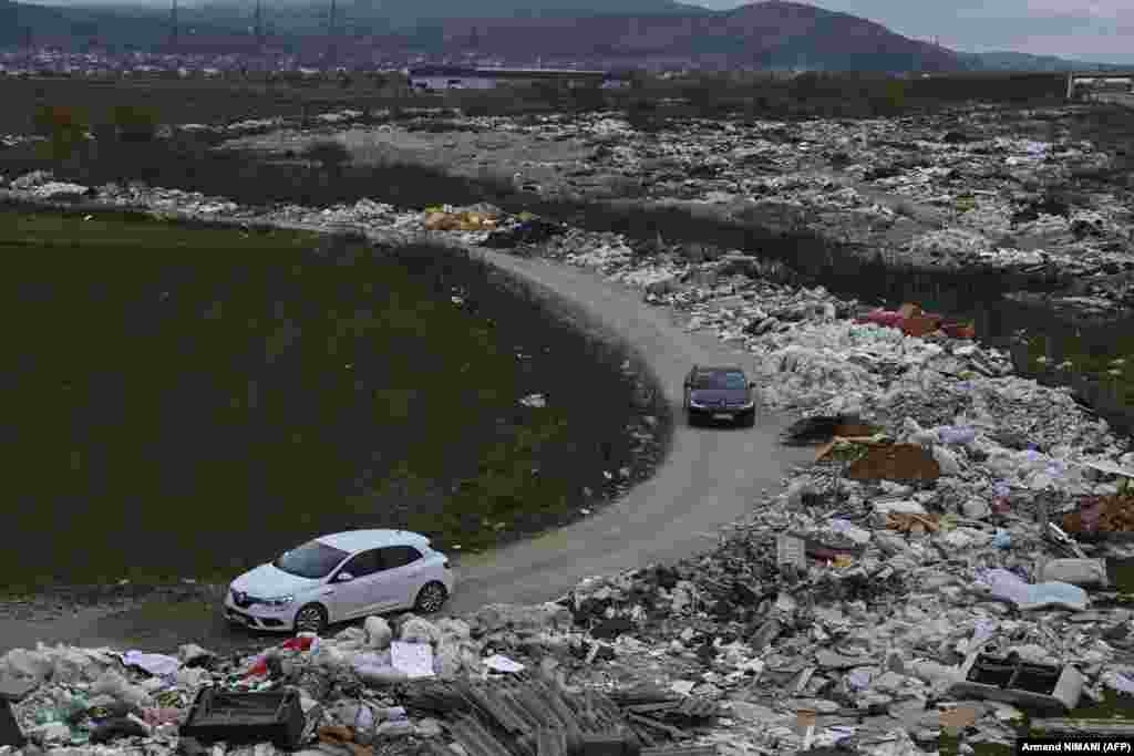 Cars drive through an illegal landfill site near Pristina.