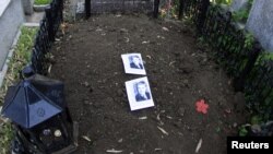 Two pictures of former communist dictator Nicolae Ceausescu lie on his grave after it was dug up to check whether it really contained his remains.