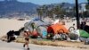 Egy futó halad el hajléktalanok tábora mellett 2021. június 8-án a kaliforniai Los Angeles Venice Beach városrészében