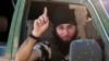 An Islamic State fighter gestures from a vehicle near the Syrian town of Kobani after IS fighters took control of the area in October 2014. When it comes to working face-to-face to deradicalize young people, there appears to be little difference between the methods used with neo-Nazis and with foreign fighters from IS or Al-Qaeda. (file photo)