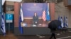 KOSOVO -- A man with an umbrella walks in front of the giant screen showing Kosovar Foreign Minister Melisa Haradinaj Stublla attending the virtual ceremony to establish diplomatic ties between Kosovo and Israel in Pristina, February 1, 2021