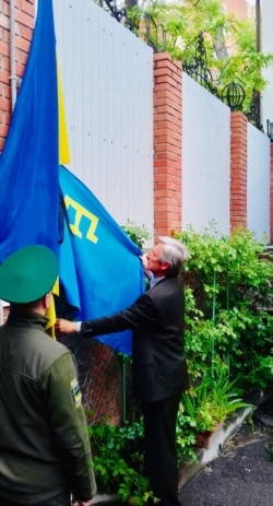 Тарас Малышевский поднимает крымскотатарский флаг на территории посольства