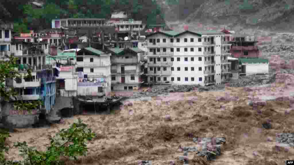 Fast-moving water from the Alaknanda River destroys building during a heavy monsoon in the Indian state of Uttrakhand. At least 18 people have been killed as the annual monsoon covered the country nearly two weeks ahead of schedule. (AFP)