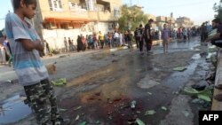 Ирачко момче гледа во улицата со крв по детониран експлозив од бомбаш самоубиец на 11 јуни 2014. 