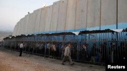 فلسطینی‌هایی که در اسرائیل کار می‌کنند، در کنار دیوار حائل برای کسب اجازه ورود به بیت‌المقدس صف کشیده‌اند