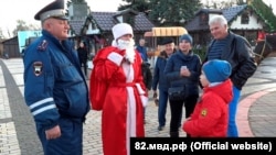 Российский полицейский в костюме Деда Мороза общается с детьми в центре Керчи, 30 августа 2017 года