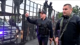 Belarusian President Alyaksandr Lukashenka, armed with a Kalashnikov-type rifle, greets riot-police officers near the Palace of Independence in Minsk amid massive opposition protests on August 23.