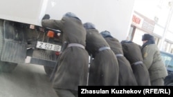 Сотрудники КУИС толкают машину с заключенными, которых везут в суд, Астана, 21 декабря 2010 года. 
