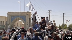Taliban fighters hoisting the group’s flag in Kandahar, which was captured on August 12.