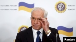 Ukraine's former Prime Minister Mykola Azarov adjusts his glasses as he attends a news conference in Moscow on August 3.