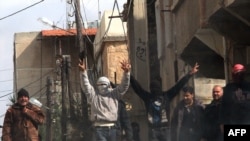 Antigovernment activists gesture during ongoing protests in Syria.