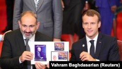 ARMENIA -- French President Emmanuel Macron (R) and Armenian Prime Minister Nikol Pashinian take part in a stamp cancellation ceremony, dedicated to French singer of Armenian origin Charles Aznavour, during the 17th Francophonie Summit in Yerevan, October