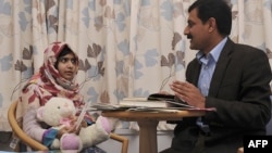 Malala Yousafzai (left) talks with her father Ziauddin at the Queen Elizabeth Hospital in Birmingham in November 2012.