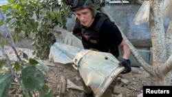 A police explosives expert carries part of a Russian glide bomb near a house hit by a Russian air strike in Kharkiv on June 27.