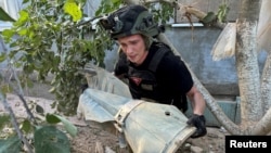 Orosz siklóbomba maradványát vizsgálja egy robbanóanyag-szakértő a Harkivot érő orosz légicsapás után, 2024. június 27-én