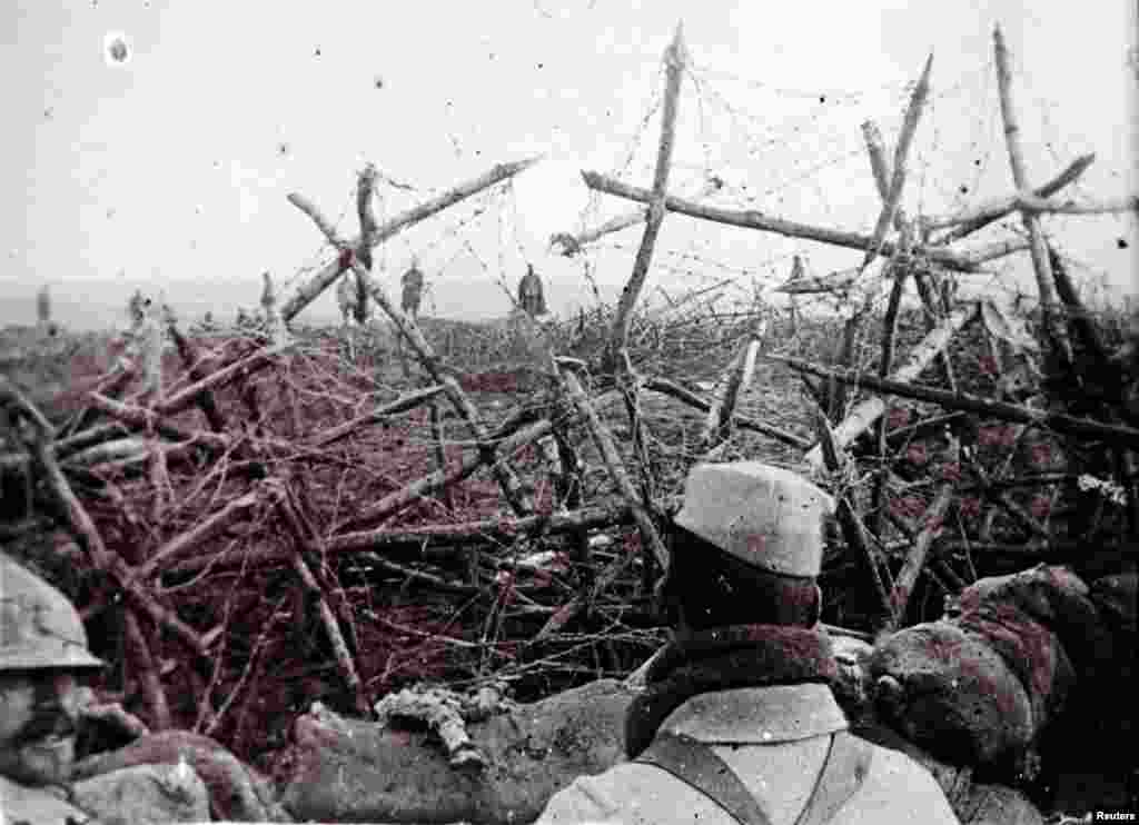 An undated photo shows German soldiers crossing a field, offering to surrender to French troops at a listening post in a trench at Massiges, France.