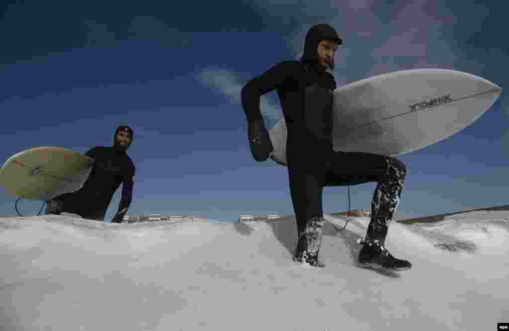 Surfers trudge through snow to reach the shore in Rockaway Beach, New York.