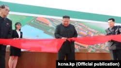 Заводдун ачылышында тасма кесип жаткан Ким Чен Ын. Пхеньян шаары, Түндүк Корея. Сүрөт маалымат каражаттарына 2-май күнү жарыяланды.