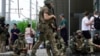 Бойцы ЧВК «Вагнер» сидят на тротуаре во время патрулирования центра Ростова-на-Дону, 24 июня 2023 года