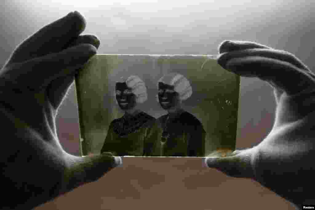 A museographer holds a glass plate negative from the "Costica Acsinte picture archive" at Ialomita county museum in Slobozia. (Reuters/Bogdan Cristel)