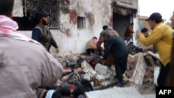 A handout picture released by the Syrian opposition Shaam News Network allegedly showing Syrians helping victims following an air strike by regime forces near a bakery in the rebel-held town of Halfaya in the central province of Hama on December 23. 