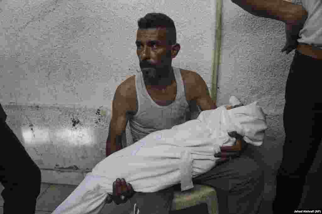 Një burrë palestinez duke mbajtur kufomën e një fëmije të vrarë nga një sulm ajror izraelit në Gazë, më 22 korrik.