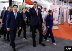 Николас Мадуро на открытии китайско-венесуэльской выставки в Каракасе вместе с главой Китайского банка развития Тань Цзюнем (слева) и тогдашним вице-президентом, ныне президентом Венесуэлы Делси Родригес (справа). 4 июля 2025 года