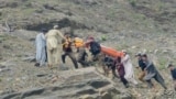 په کوهستان کې مرستندویه کارکوونکي او ځايي خلک د ټرافیکي پېښې ښکار شوی کس امبولانس ته انتقالوي - د مې لومړۍ نېټې انځور. 