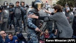 Demonstrant polisiýa işgärini saklamaga synanyşýar. 19-njy aprel, 2018 ý.