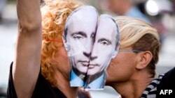 Manifestante în Paris, purtând măști cu Vladimir Putin, se sărută în fața ambasadei Rusiei, pentru a protesta împotriva legilor rusești "anti-gay".