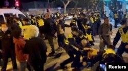 Ofițeri de poliție rețin manifestanții din Shanghai, 27 noiembrie 2022. Nemulțumirea oamenilor din China a luat amploare după incendiul din Urumqi, unde zece persoane au murit deoarece nu au avut voie să iasă din casă, ca urmare a măsurilor anti-Covid.
