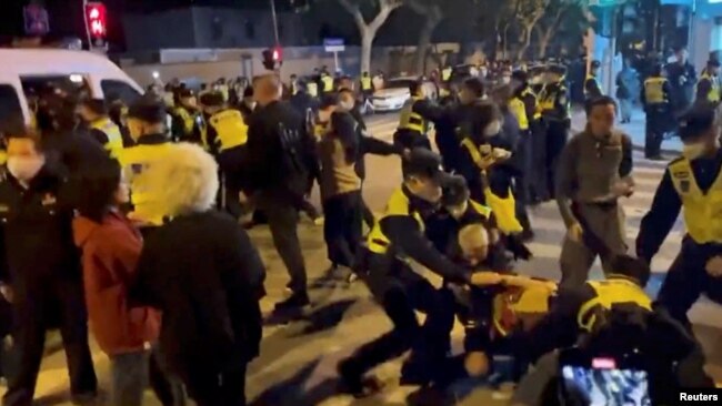 Ofițeri de poliție rețin, la Shanghai, protestatari adunați la un priveghi pentru victimele incendiului de la Urumqi. Protestele din ultimele zile din China sunt fără precedent în regimul lui Xi Jinping. (Captură video)