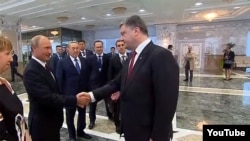Президент России Владимир Путин (слева) и президент Украины Виктор Порошенко (справа) пожимают руки на встрече в Минске, 26 августа 2014 года. 