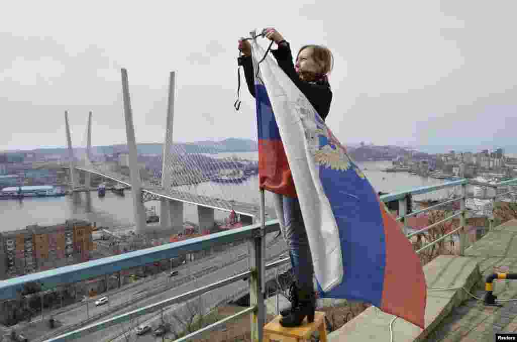 A woman attaches a black ribbon for those killed in the sinking of Dalniy Vostok to a Russian national flag in Vladivostok on April 7. (Reuters/Yury Maltsev)