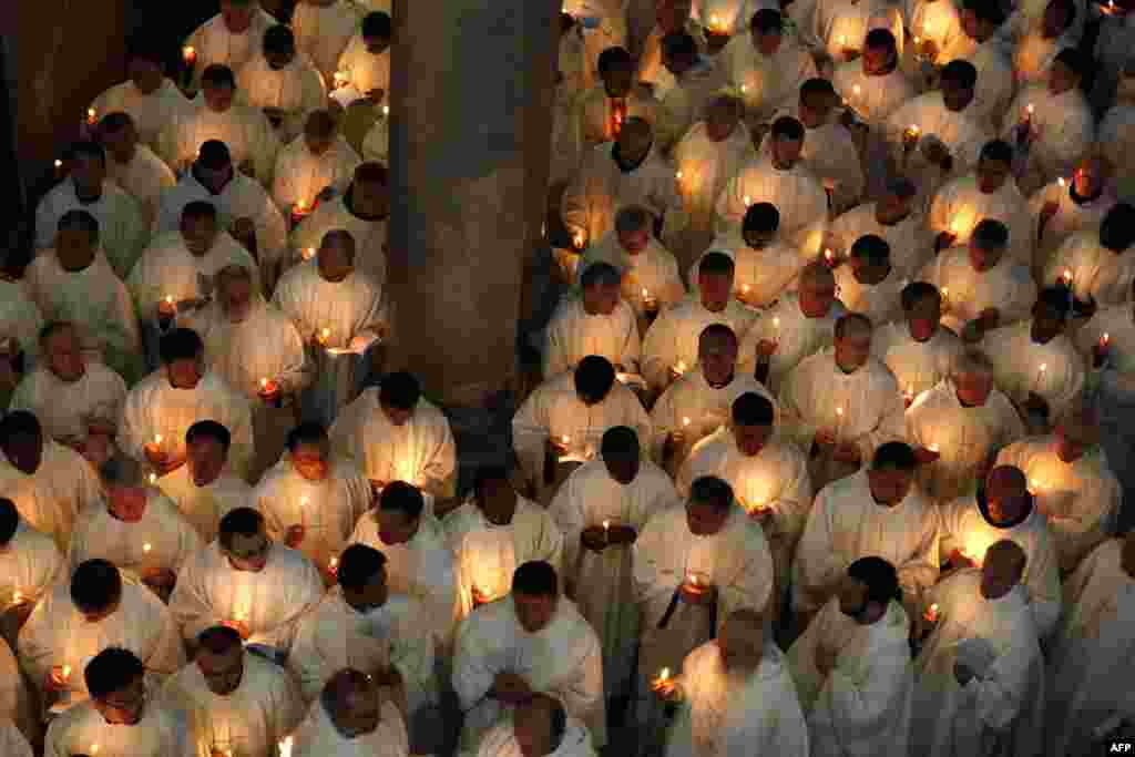 Roman Catholic clergymen hold candles as they circle the Anointing Stone during the Holy Thursday Mass at the Church of the Holy Sepulchre in Jerusalem&#39;s old city. (AFP/Gali Tibbon)