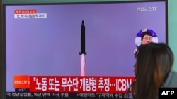 A South Korean woman in Seoul walks past a television screen showing file footage of North Korea's test missile launch on February 11. 