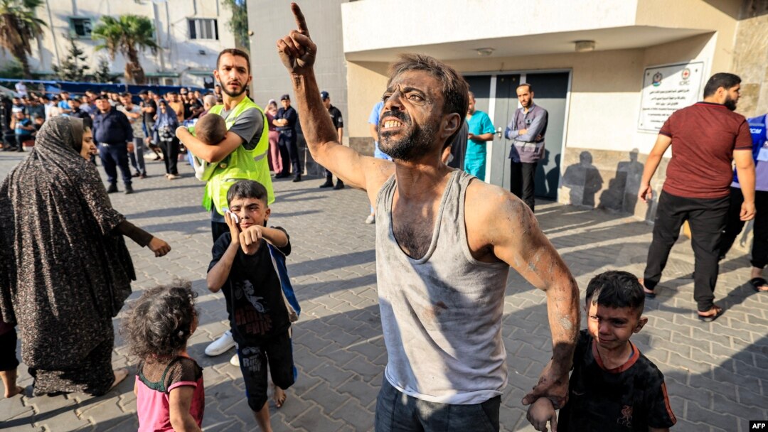 Un bărbat palestinian ține de mână un copil în timp ce gesticulează în fața spitalului al-Shifa din orașul Gaza, pe 12 octombrie 2023. Luptele violente dintre Israel și mișcarea Hamas continuă pentru a șasea zi consecutivă.