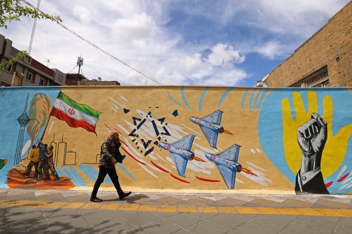 A man walks past an anti-American and anti-Israeli mural in Tehran on April 8, 2026.