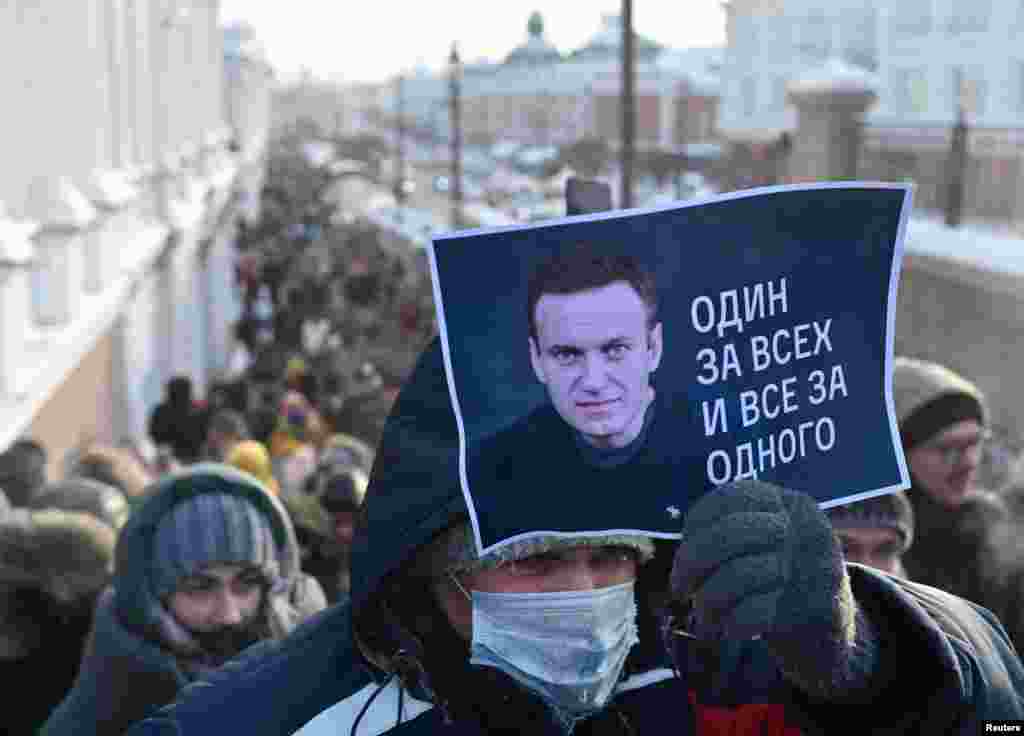 Омбыда наразылыққа шыққан адам &quot;Біріміз - бәріміз үшін, бәріміз - біріміз үшін&quot; деген жазу жазылған&nbsp;Навальныйдың суретін ұстап тұр.