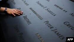 Жінка кладе руку на вигравірувані імена загиблих від терактів 11 вересня, Меморіальний музей жертв, Нью-Йорк, 2014 рік