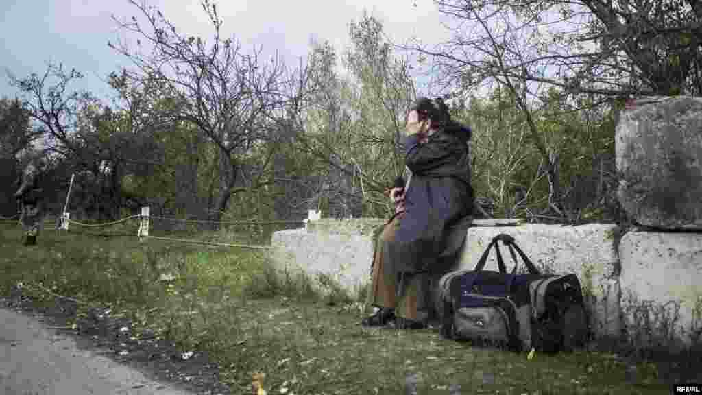 У режимі очікування. Жінка старшого віку присіла перепочити на переході між контрольними пунктами бойовиків та українських військових