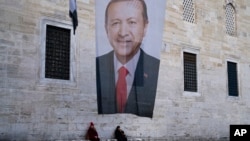 Dy gra ulen pranë një afisheje zgjedhore të presidentit turk dhe liderit të Partisë për Drejtësi dhe Zhvillim, AKP, Recep Tayyip Erdogan, Stamboll, Turqi, 11 mars 2024.