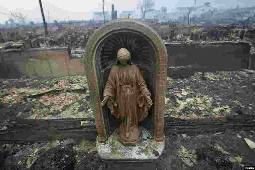 OCTOBER 30, 2012 -- A statue is seen among homes devastated by fire and the effects of Hurricane Sandy in the Breezy Point section of the Queens borough of New York City. (Reuters/Shannon Stapleton)