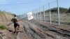 A Hungarian soldier carries a border sign to install at a fence near the town of Morahalom, at the Serbian border, on August 24.