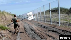 A Hungarian soldier carries a border sign to install at a fence near the town of Morahalom, at the Serbian border, on August 24.