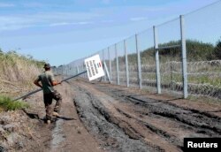 A Hungarian soldier carries a border sign to install at a fence near the town of Morahalom on August 24.