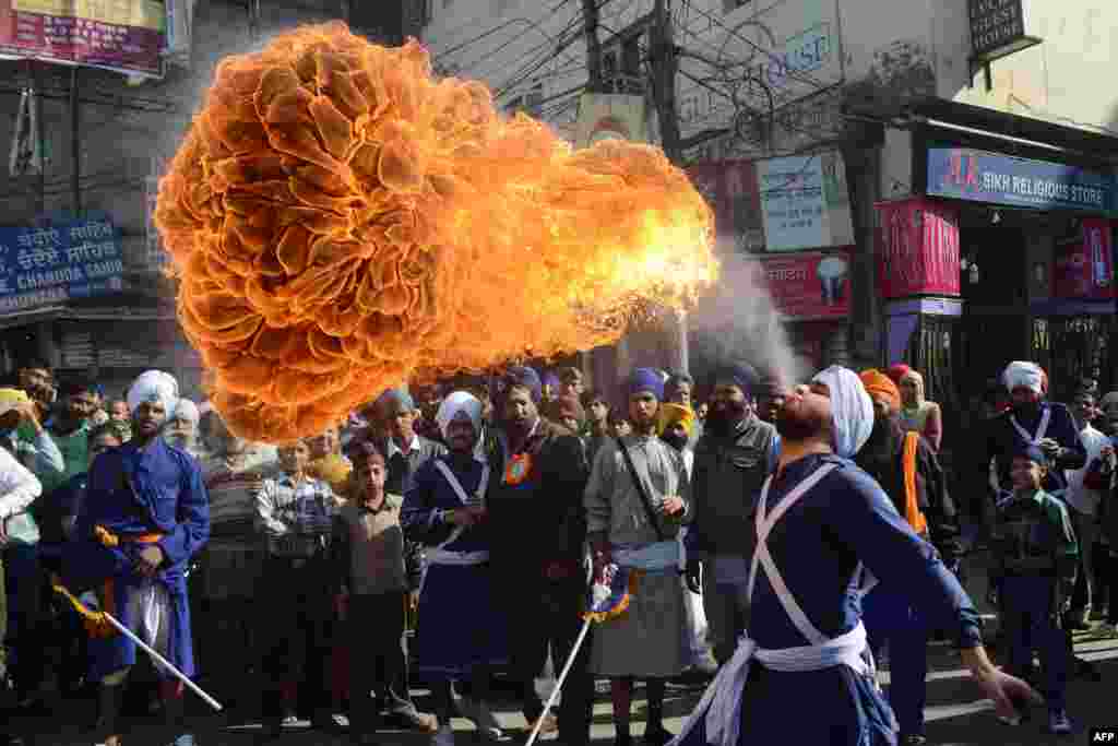 An Indian Sikh performs a fire-breathing act at a demonstration of skills during a procession from Sri Akal Takhat to the Golden Temple in Amritsar on the eve of the 543rd birth anniversary of Sri Guru Nanak. Guru Nanak was the founder of the religion of Sikhism and the first of 10 Sikh gurus. (AFP/Narinder Nanu)